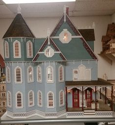 a blue doll house with red doors and windows on display in a toy store or playroom