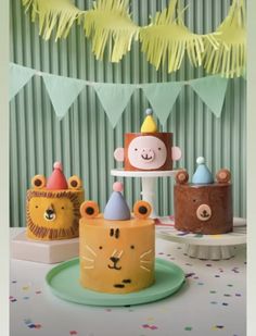 three cakes with animals on them sitting on top of a cake plate in front of a party banner