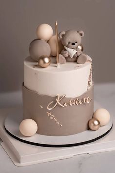 a white and grey cake with a teddy bear on top