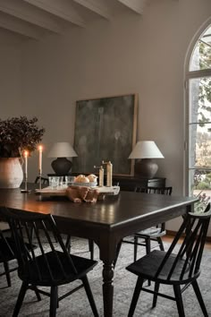 a dining room table and chairs with candles on it