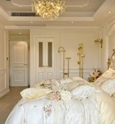 a bed with white sheets and pillows in a bedroom next to a chandelier