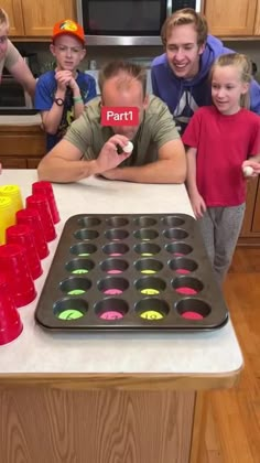 a group of people standing around a table with cupcake pans on top of it