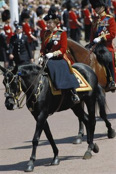 two men in uniform riding on the backs of horses with other uniformed people behind them