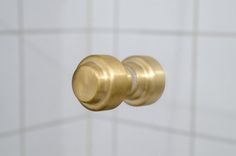 a close up view of a gold door knob on a white tile wall with lines in the background