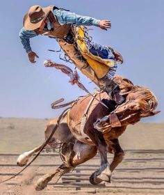 a man riding on the back of a brown horse while flying through the air over a dirt field