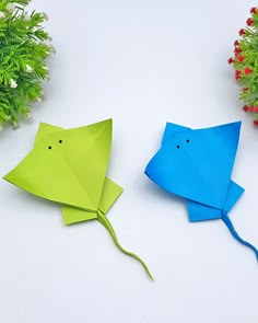 two origami fish sitting next to each other on top of a white table