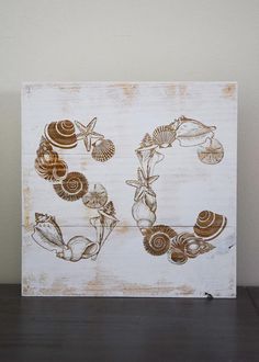 a wooden sign with seashells and shells painted on it