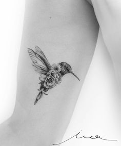 a small hummingbird with flowers on its back leg tattoo by the talented artist jane