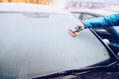 a person cleaning the windshield of a car