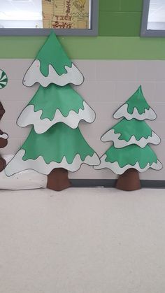 a teddy bear sitting on the floor next to two christmas trees with candy canes