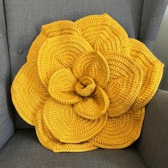 a yellow knitted flower sitting on top of a gray chair