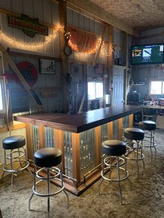 a bar with four stools in front of it and lights hanging from the ceiling