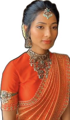 a woman in an orange and gold sari with jewelry on her neck, standing against a white background