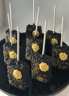 black and gold desserts with white candles on a cake platter, ready to be eaten