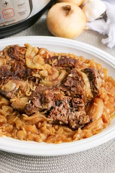 a white plate topped with meat and onions next to an instant pot roasting machine