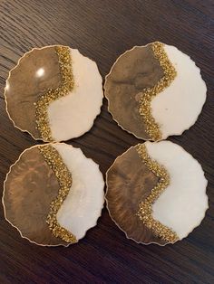 four plates with gold glitters on them sitting on a wooden table next to each other