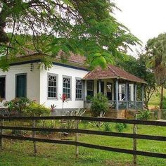 a small white house sitting next to a wooden fence