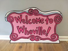 a sign that says welcome to whovillee on the side of a wooden floor