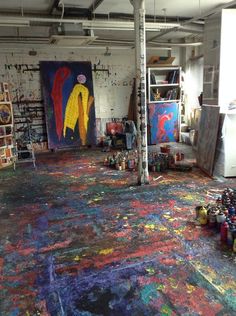 an artist's studio filled with lots of art supplies and paintings on the walls