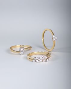 three different types of wedding rings on a white surface with one diamond in the middle