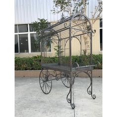 a wrought iron bed frame with wheels in front of a building