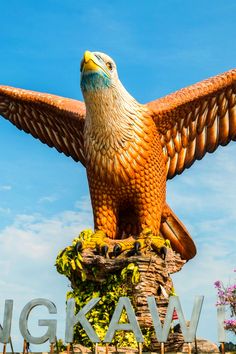 a large bird statue sitting on top of a wooden post with its wings spread out