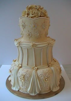 a three tiered white wedding cake with gold flowers on the top and bottom layer