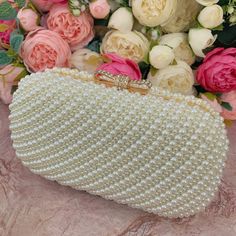 This luxurious encrusted pearl bridal clutch never fails to turn heads with its understated elegance and classic design. Adorned with varying sized ivory pearls and enhanced with a large creamy pearl clasp, this bridal clutch is the very picture of refinement. This elegant bridal clutch features rose gold trim, attachable chain and large enough for your phone. Complete your list of must-have wedding accessories with the ultimate bridal accessory to finish off your look and storing your wedding d Pearl Embellished Clutch, Pearl Clutch For Party, Elegant Pearl Evening Bag For Party, Formal Gold Clutch With Pearl Material, Elegant Pearl Evening Bag For Events, Formal Pearl White Evening Bag, Pearl Evening Bag With Pearl Handle, Pearl Evening Bag With Pearl Handle For Wedding Guest, Glamorous Pearl Clutch With Pearl Handle