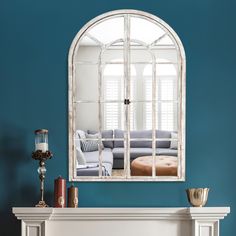 a living room with blue walls and a white fireplace mantel topped with a mirror