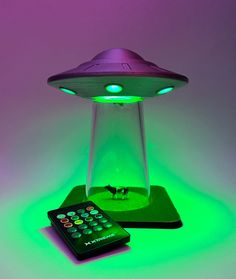 a remote control sitting on top of a table next to a green light under a flying saucer