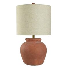 a lamp that is sitting on top of a white surface with a beige shade over it