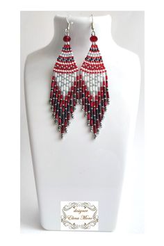 a pair of red and white beaded earrings on a mannequin head stand