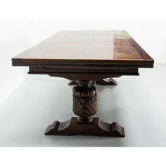 a wooden table with two faces on the top and one at the base, sitting against a white wall