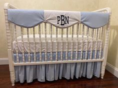 a white crib with blue ruffles and the word pn on it