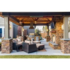 an outdoor kitchen and living room with stone fireplaces, patio furniture and grill area