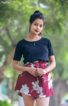 a young woman is posing for the camera wearing a short skirt and black top with white flowers on it