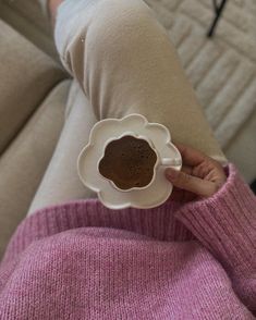 a person is holding a coffee cup in their left hand while sitting on the couch