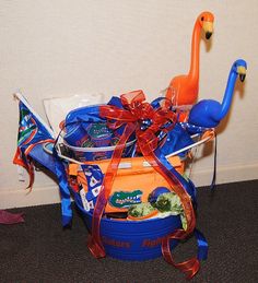 a blue bucket filled with candy and an orange flamingo sitting on the floor next to a wall