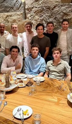 a group of men sitting around a table with plates of food and drinks on it