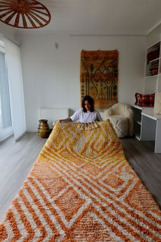 a woman laying on top of a large orange and white rug