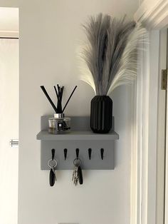 a wall mounted shelf with keys and other items on it next to a toilet in a bathroom