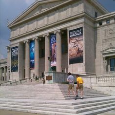 two men walking up and down the steps in front of a large building with columns