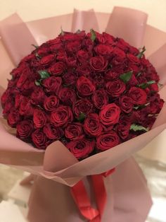 a bouquet of red roses is wrapped in pink paper