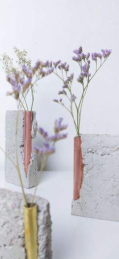 two vases with flowers in them sitting next to each other on a white surface