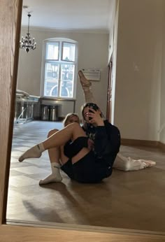 two people sitting on the floor in front of a mirror