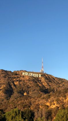 the hollywood sign on top of a hill with trees around it and a radio tower in the distance