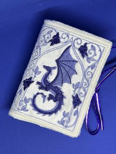 a blue and white embroidered book with a dragon on it's cover sitting on a blue surface