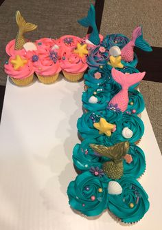 cupcakes with blue frosting and pink icing are arranged in the shape of a mermaid tail