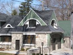 a stone house with green shingles on the roof