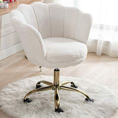 a white chair sitting on top of a rug in front of a desk and window